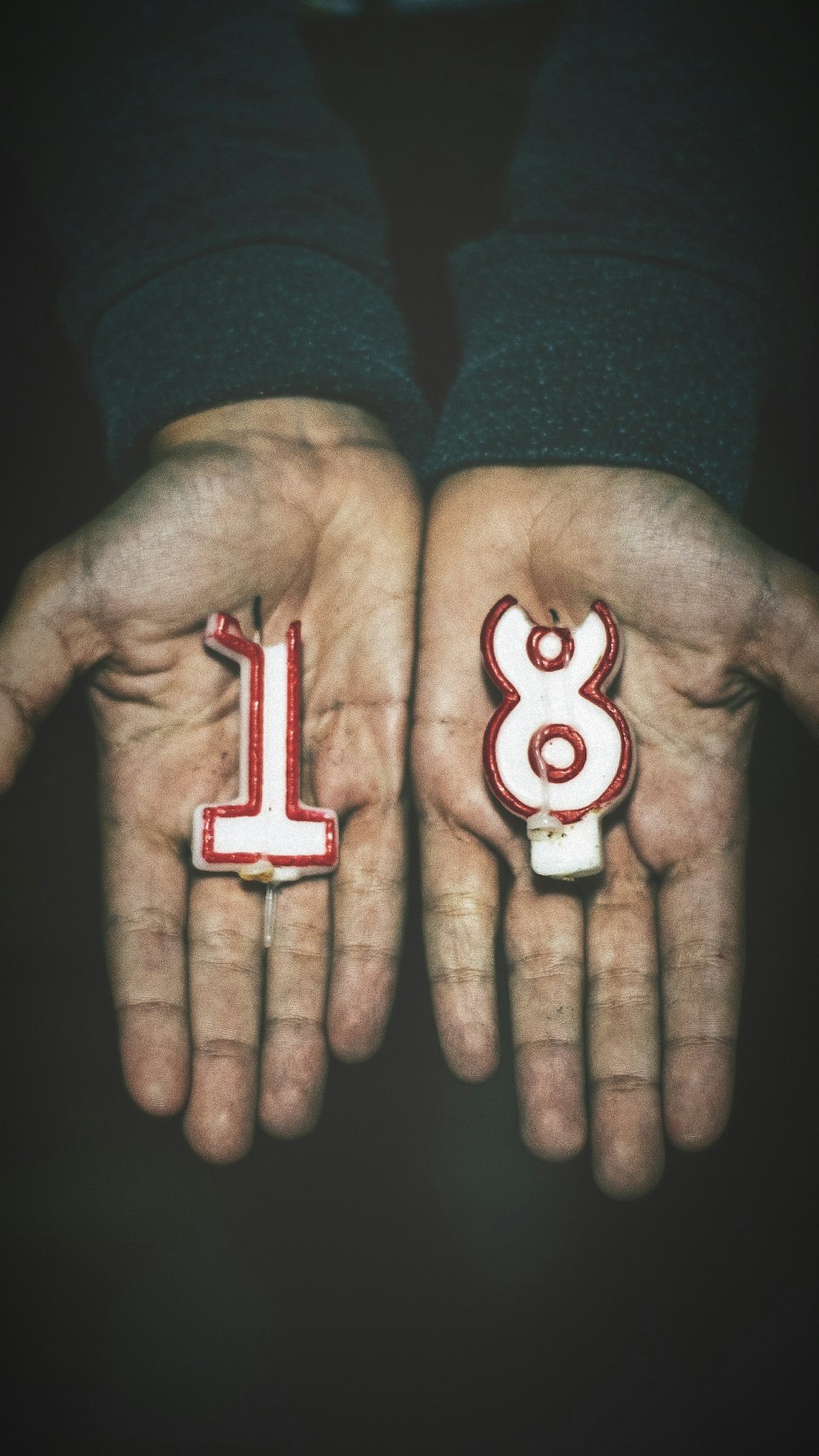 person holding number 1 and 8 candles