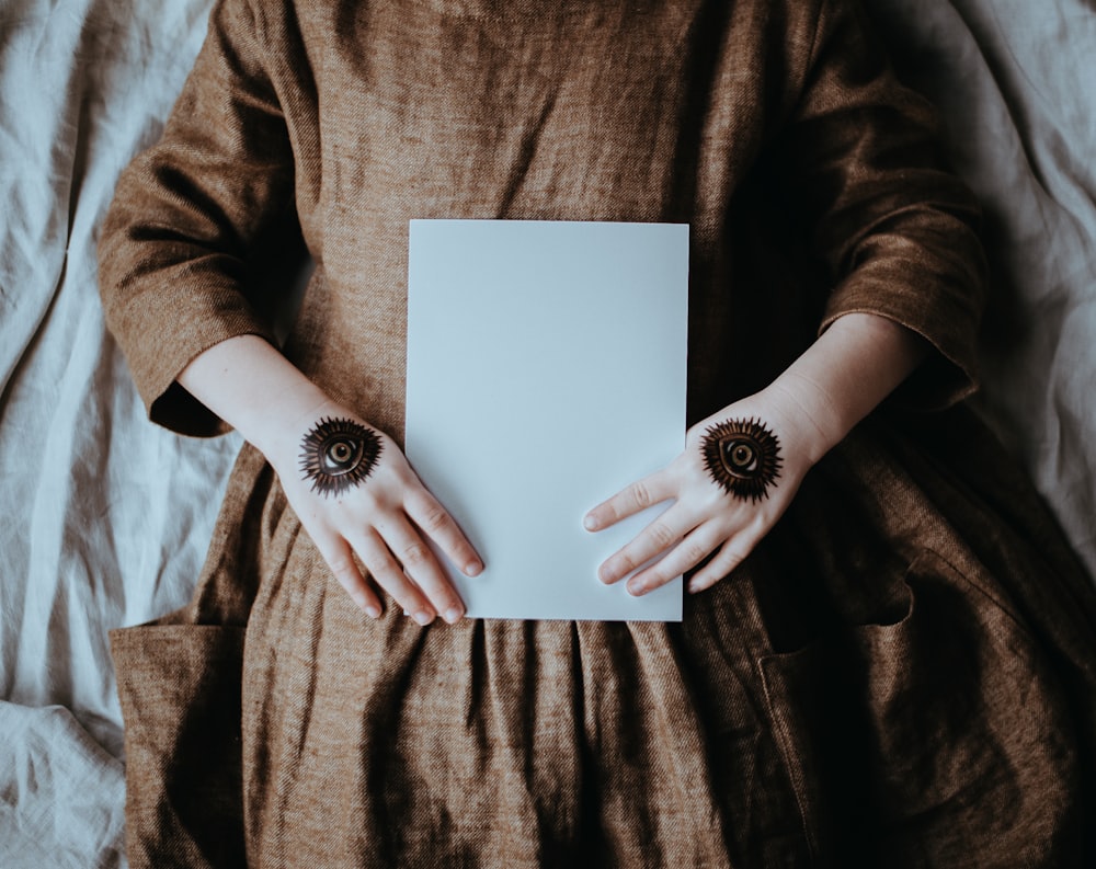 woman lying on bed holding white printer paper