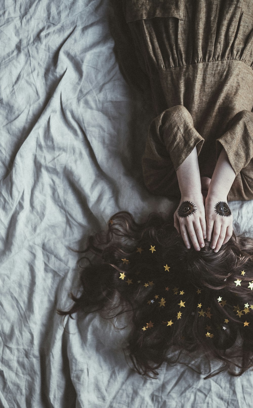 woman lying on bed while covering her face