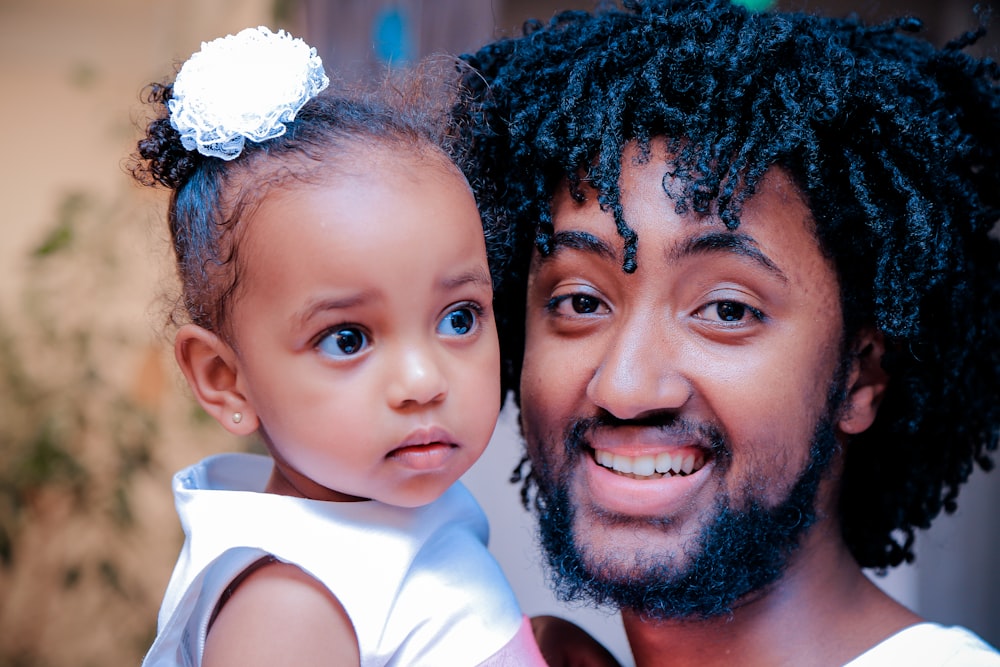 man in white top holding girl baby