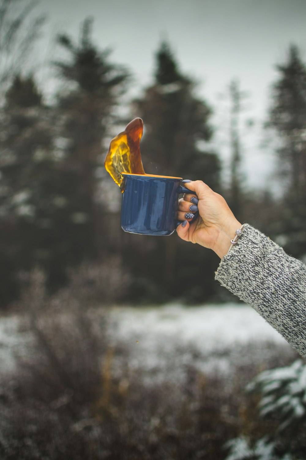 time lapse photo of woman holding blue ceramic mug with coffee spilled upward