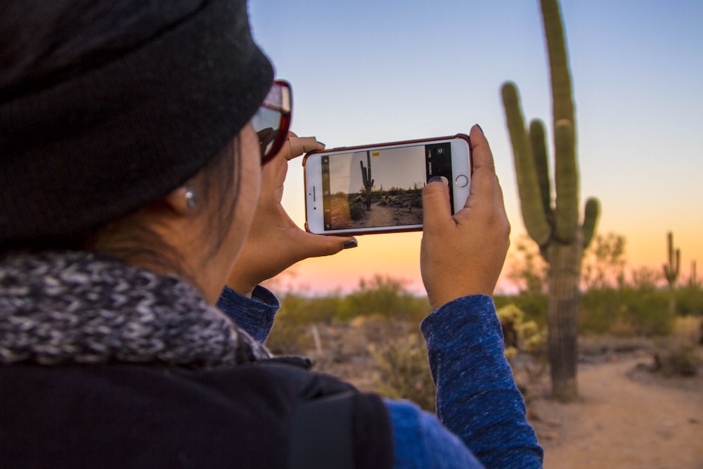 woman using iPhone capturing picture of cactus plant