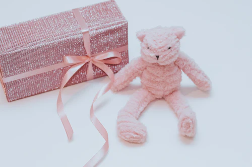 Roze knuffelbeer naast een cadeaudoos