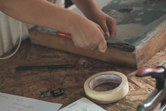 person holding pliers near adhesive tape