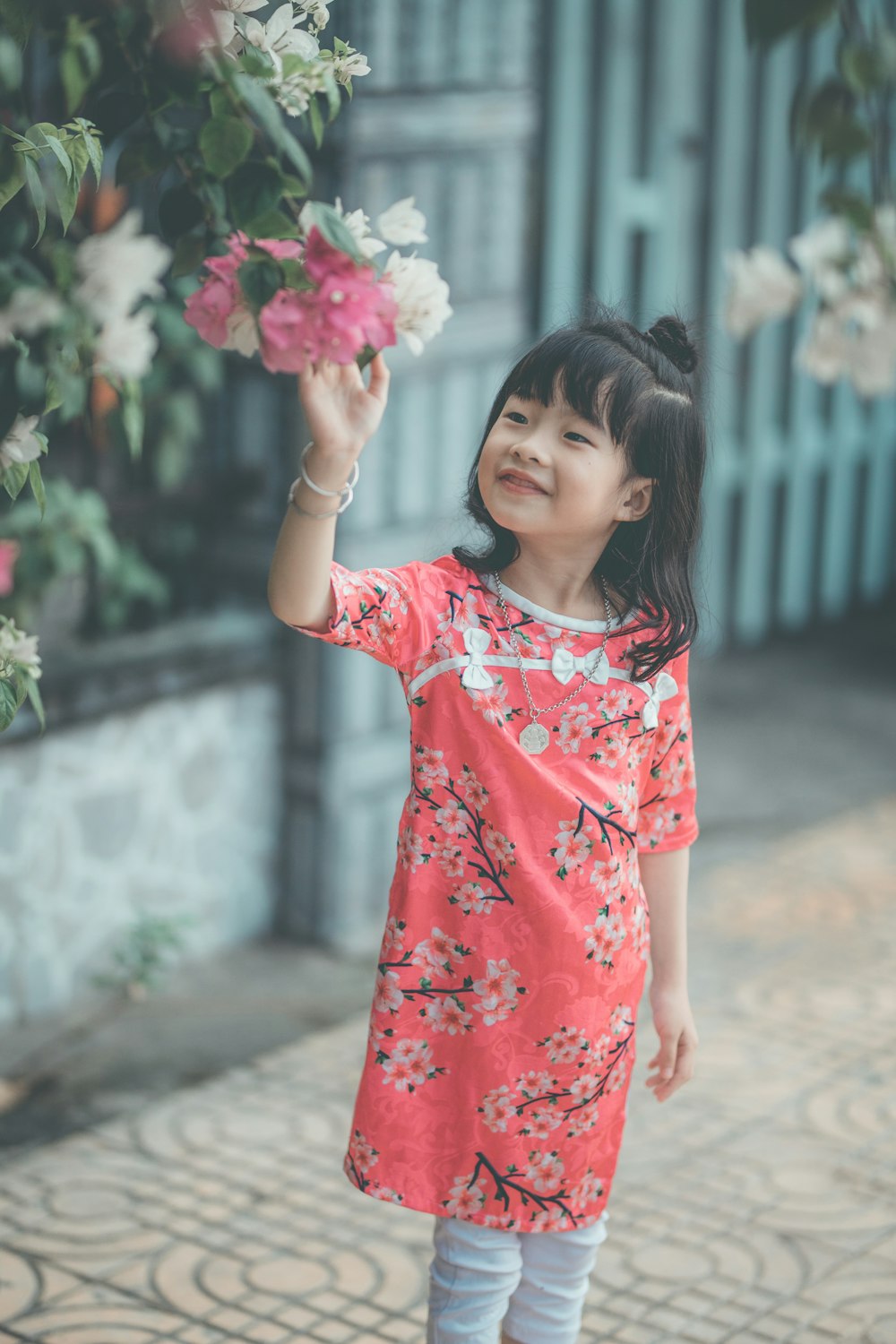 girl standing about to touch flower