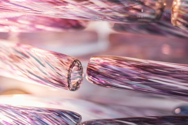 Close-up view of intricately detailed glass rods featuring a swirling pattern with a glossy finish. The rods exhibit a blend of colors that merge together to create an iridescent effect, emphasizing the delicate craftsmanship.