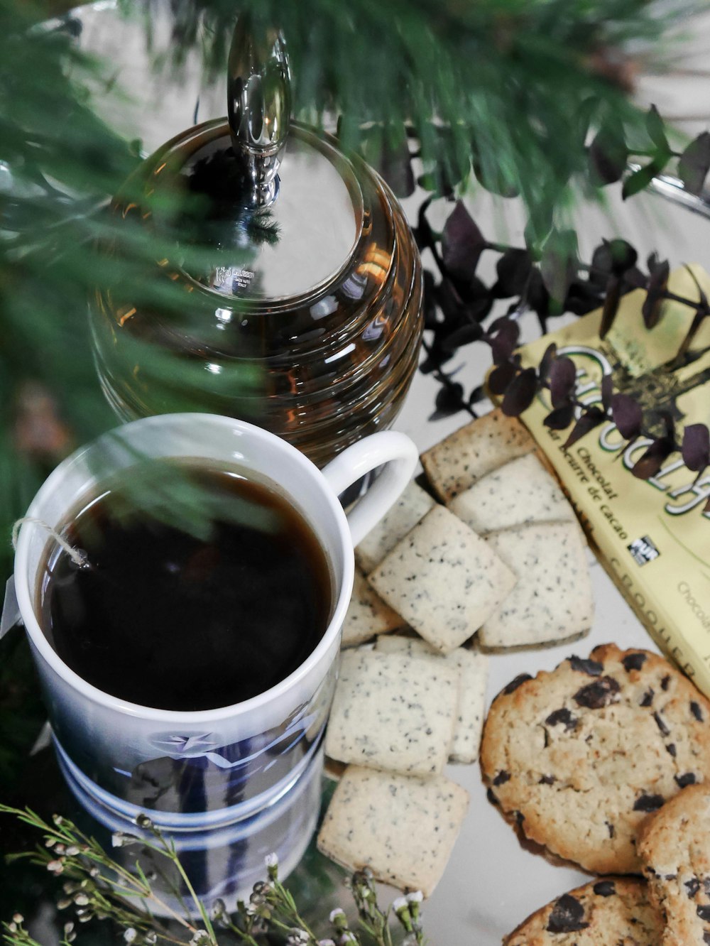 white ceramic mug with coffee beside of biscuits