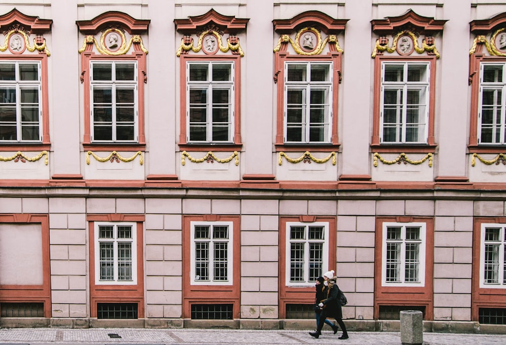 woman walking beside pink building