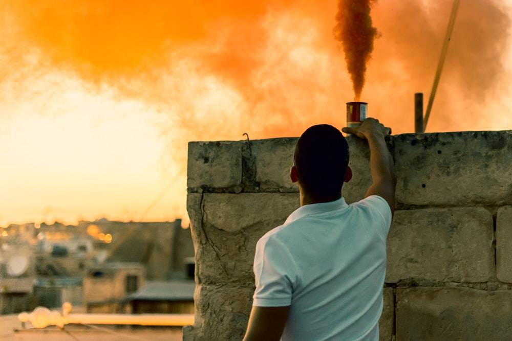 man putting on top of the cinder block wall a smoke bomb