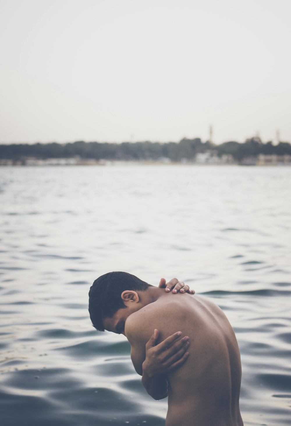 topless man beside body of water