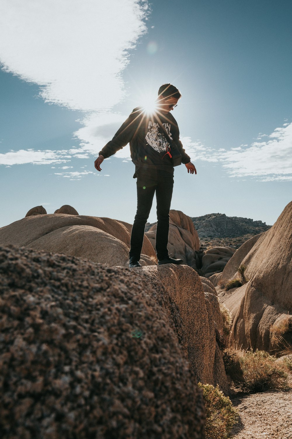 man looking down and standing on elevated rocky surface during daytime