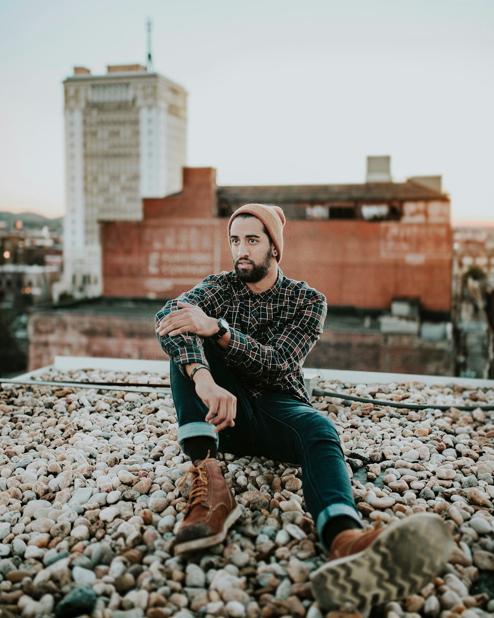 man in black and brown dress shirt seating on rocks