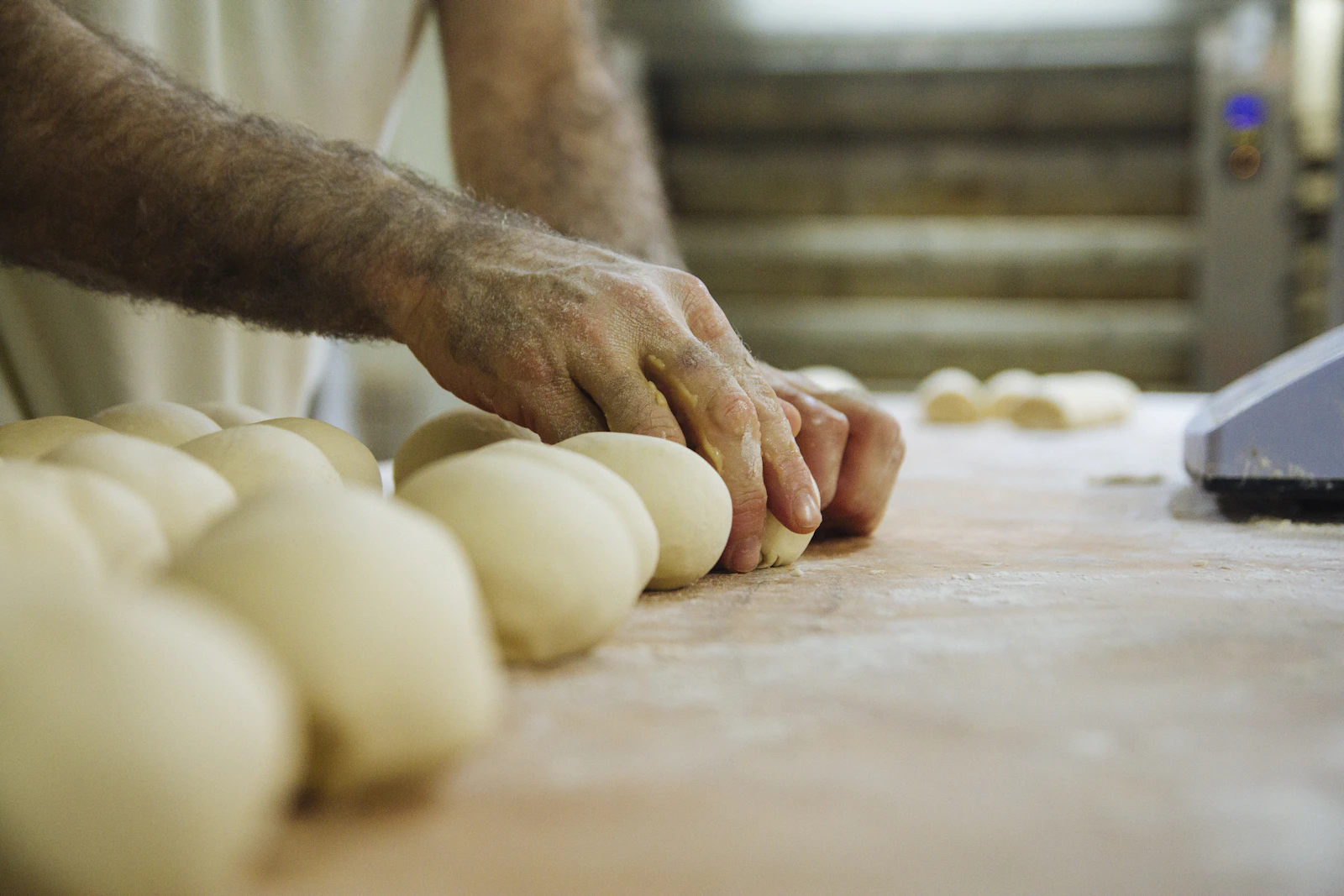 Hands kneading and shaping dough on a bakery counter