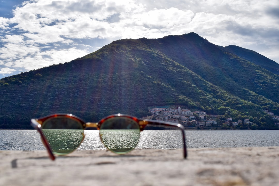gold-colored framed sunglasses facing green mountain at daytime