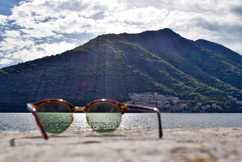 occhiali da sole con montatura color oro rivolti verso la montagna verde di giorno