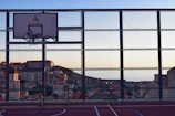 Players mid-game on a rooftop court surrounded by cityscape views at sunset.