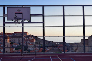 Players mid-game on a rooftop court surrounded by cityscape views at sunset.