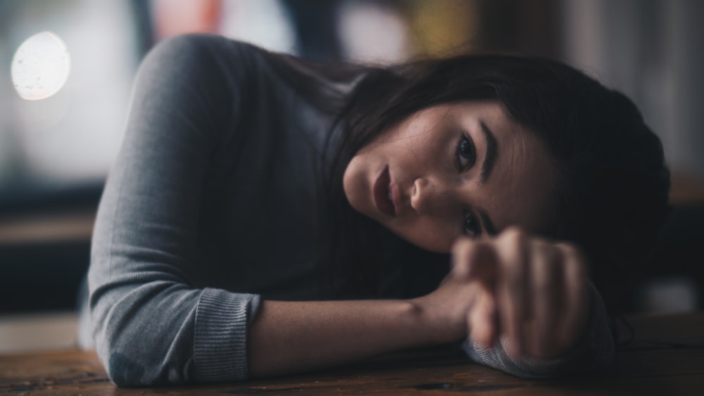 woman leaning on brown wooden surface