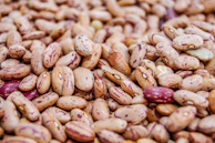 Close-up of plump dried beans in earthy tones spilling from a burlap sack.