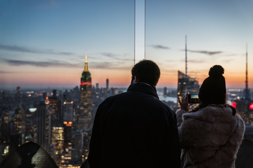man and woman taking photo on high-rise buildings