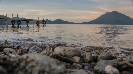 brown wooden dock over body of water and mountain during daytime in Lake Atitlán Guatemala