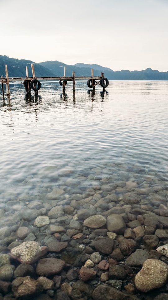 dock on water with stone at daytime in Lake Atitlán Guatemala