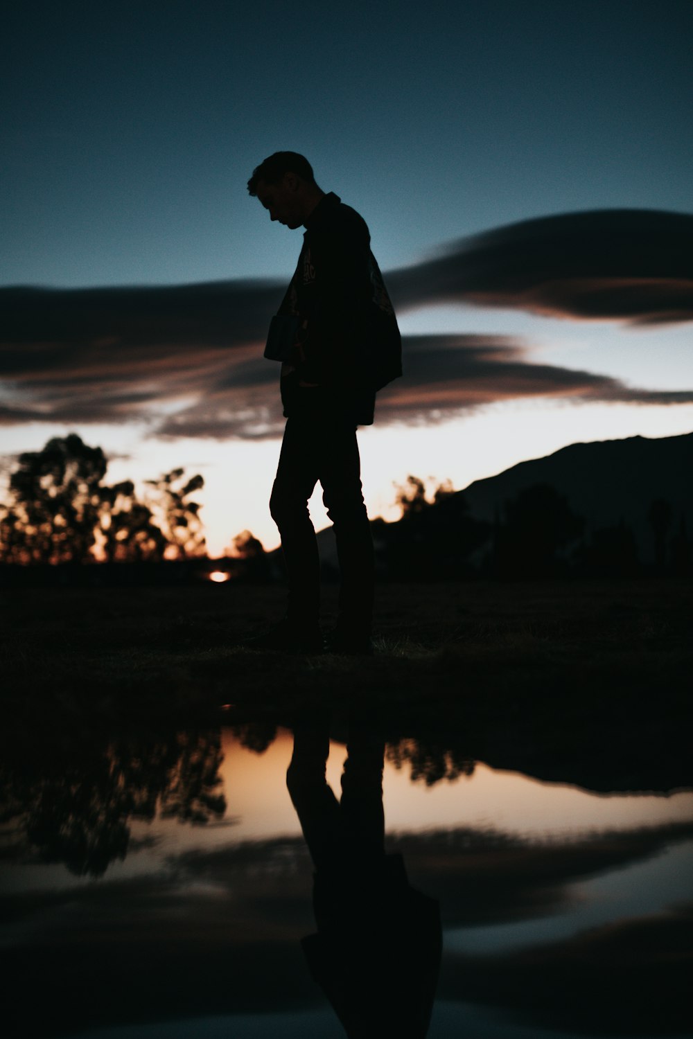 silhouette dell'uomo vicino allo specchio d'acqua