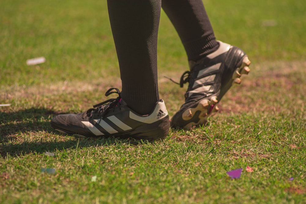 person wearing black-and-white adidas cleats standing on field