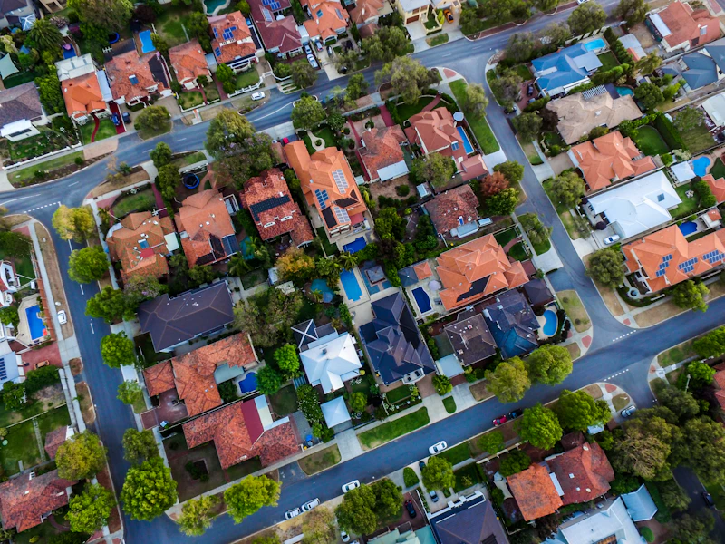 An Australian suburb from above, rooftops, pools and solar panels in the sun
