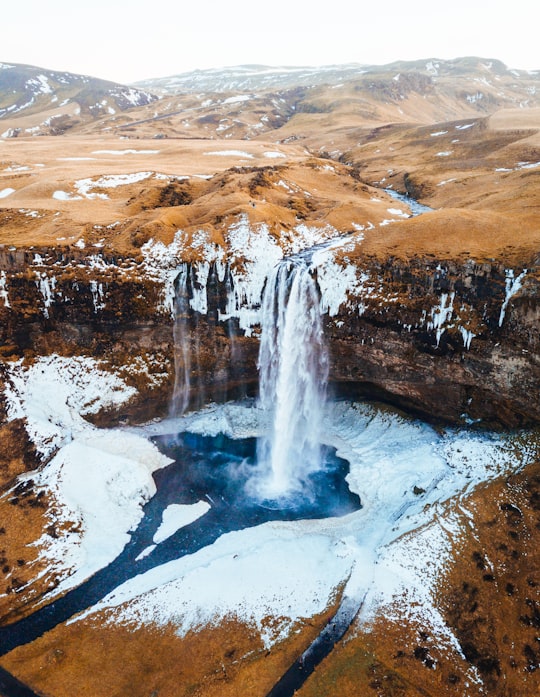 aerial photography of waterfalls near mountains at daytime in Seljalandsfoss Iceland