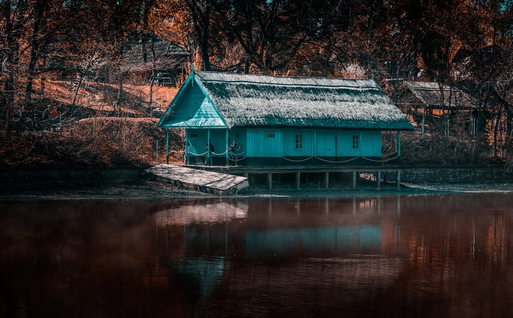 blue wooden house near body of water during daytime