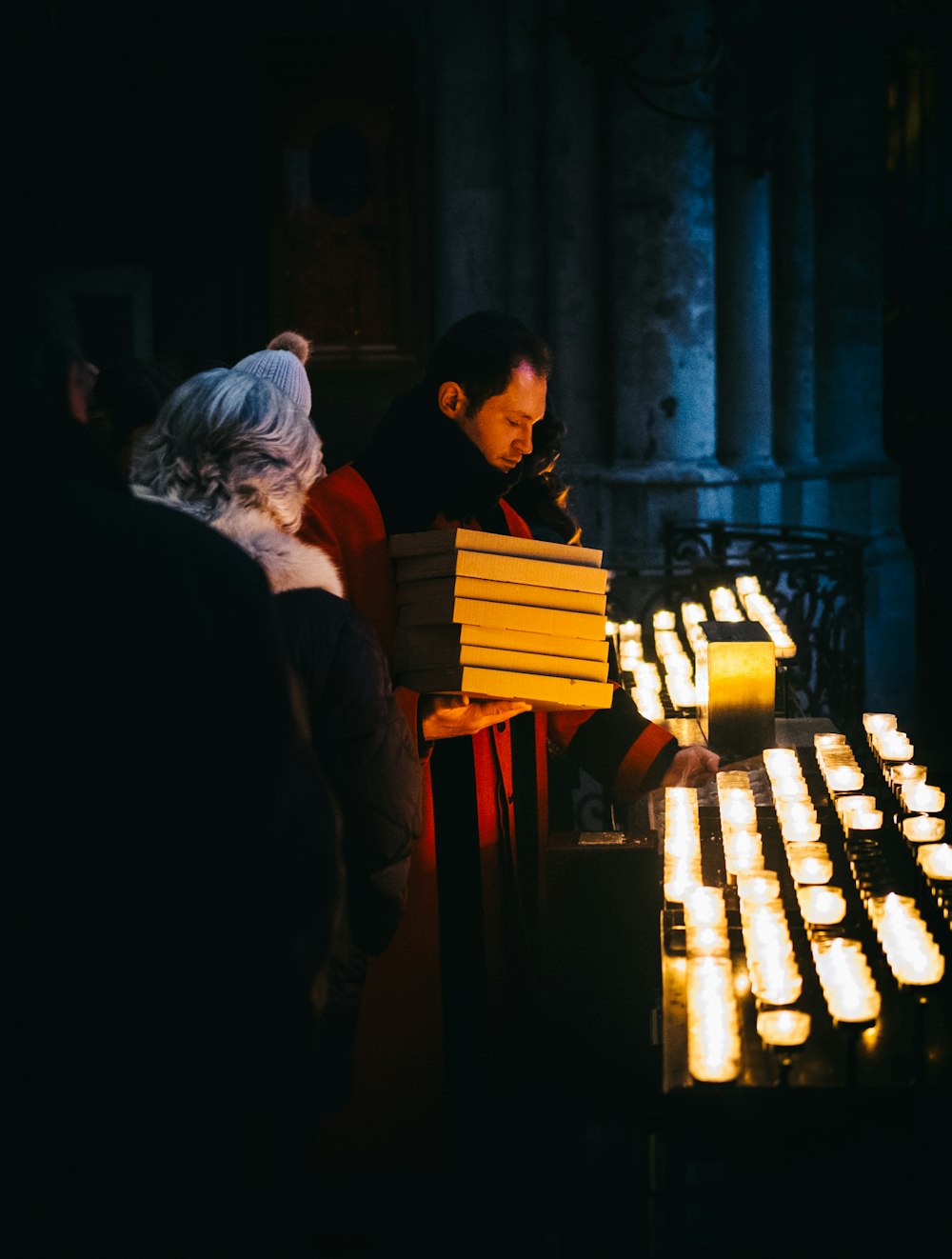 man in red coat holding white boxes holding candle