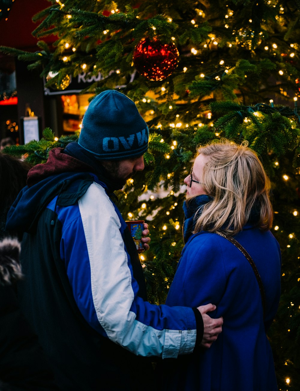 man and woman looking face to face near christmas tree