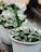 A close-up of a beautiful fiber pot filled with vibrant green plants, against a sky blue background.