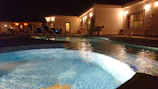 Evening scene of a pool area illuminated by warm, ambient lighting and architectural details.
