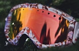 shallow focus photography of pink, orange, and green snow goggle
