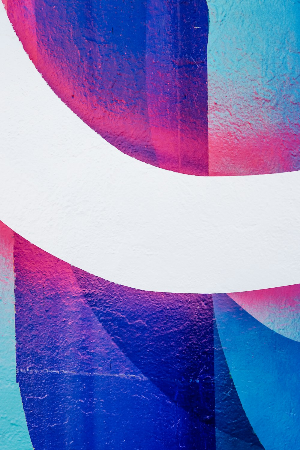 Une peinture abstraite bleue et rose sur un mur