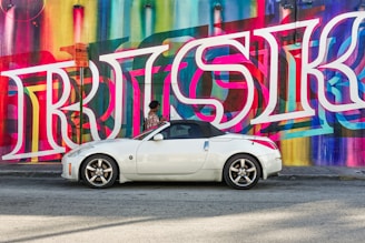 white coupe beside Risk LED signage