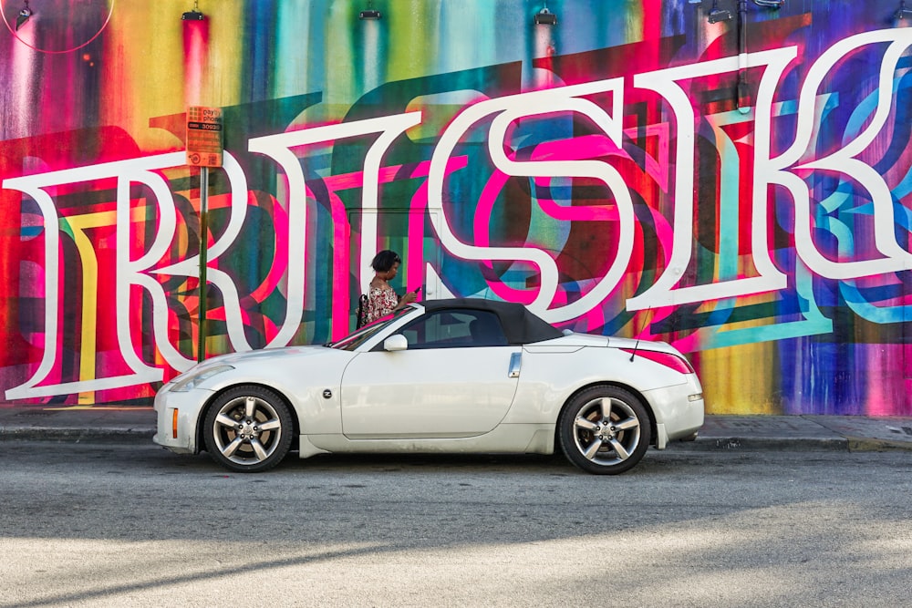 white coupe beside Risk LED signage