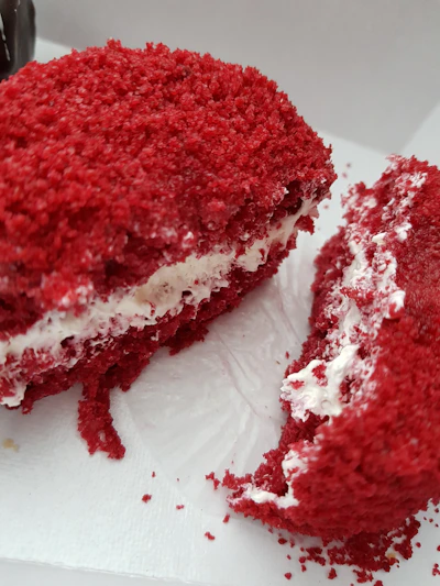 Close-up of a rich, red velvet cake with creamy frosting and delicate crumbs on a rustic wooden table