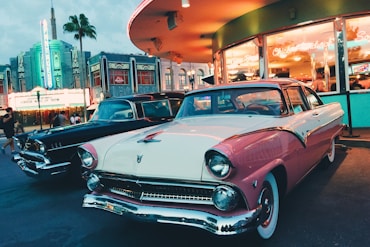 white and pink coupe parked beside black car