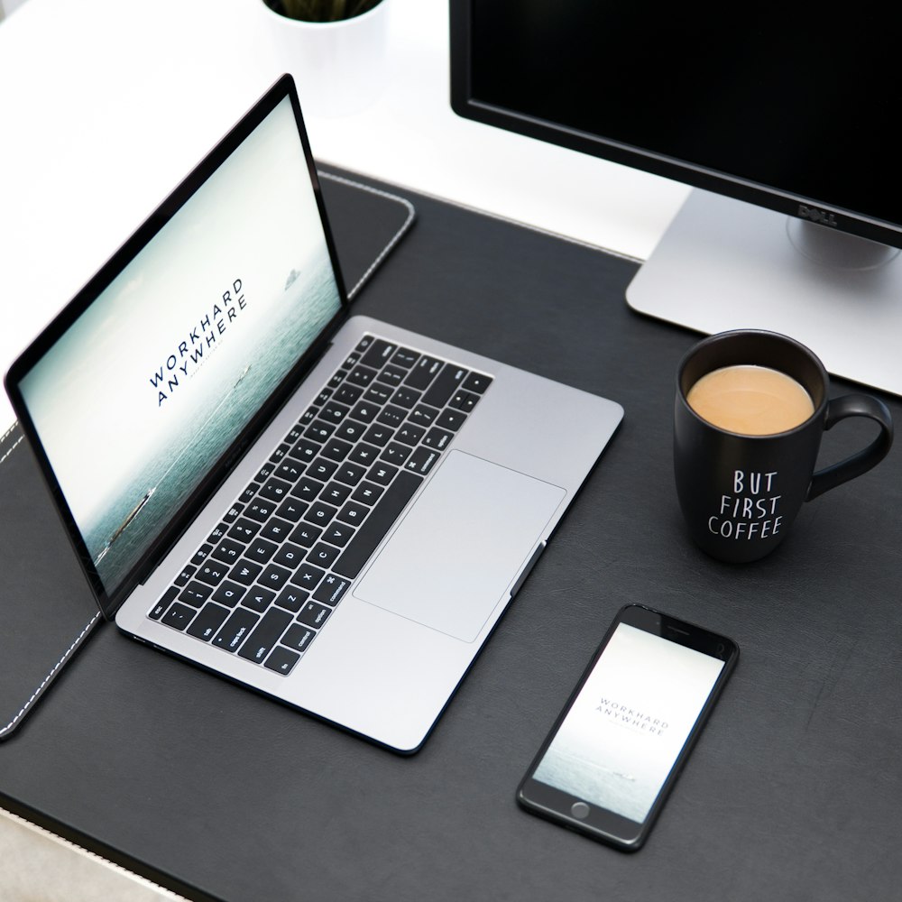 laptop, coffee mug, and iPhone on desk