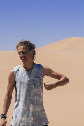 Lifestyle shot of a person wearing layered macramé jewelry, standing against a backdrop of Mexican desert plants.