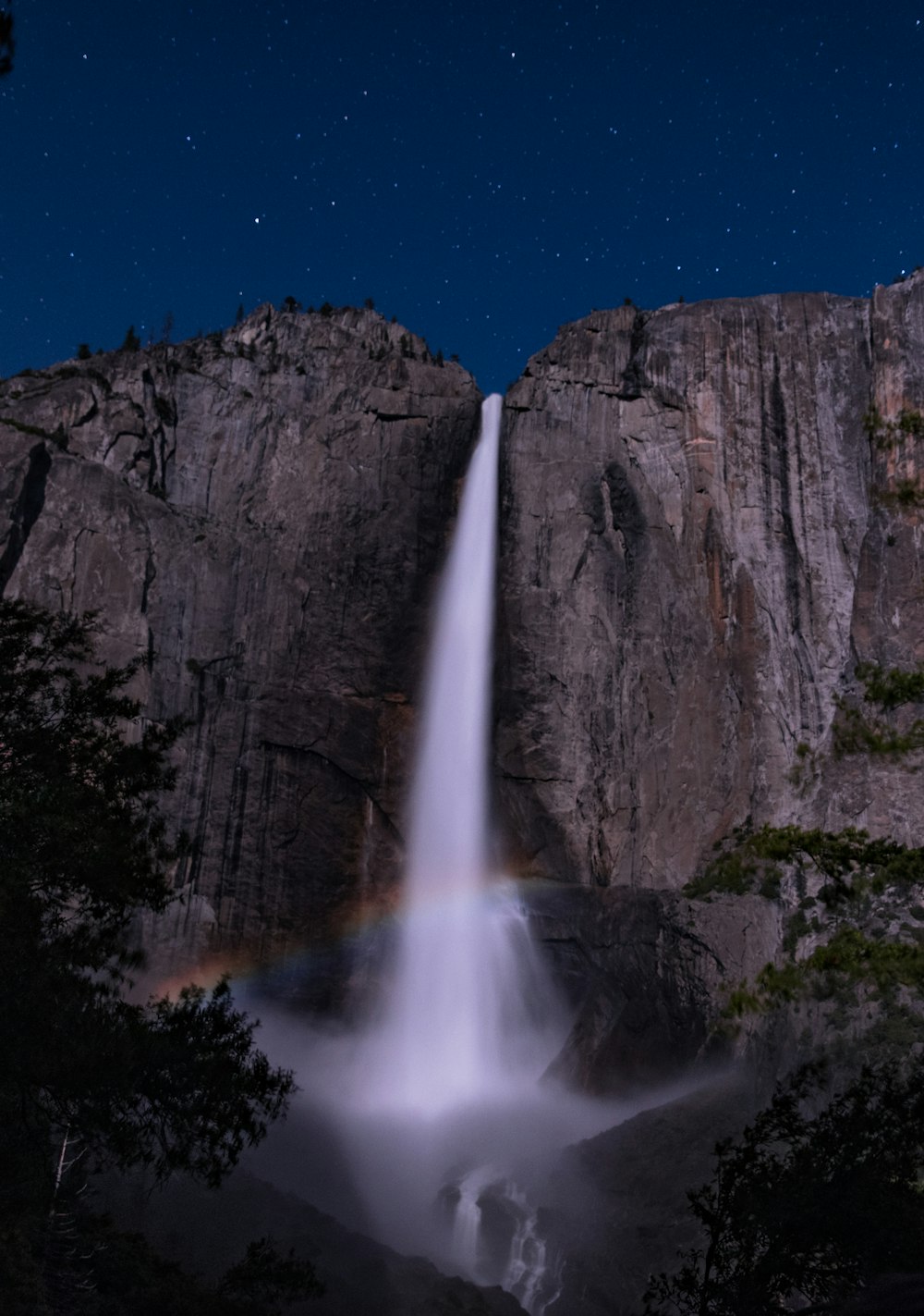 rainbow in front of waterfalls at night time