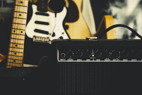 black guitar amplifier beside electric guitar