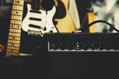 black guitar amplifier beside electric guitar