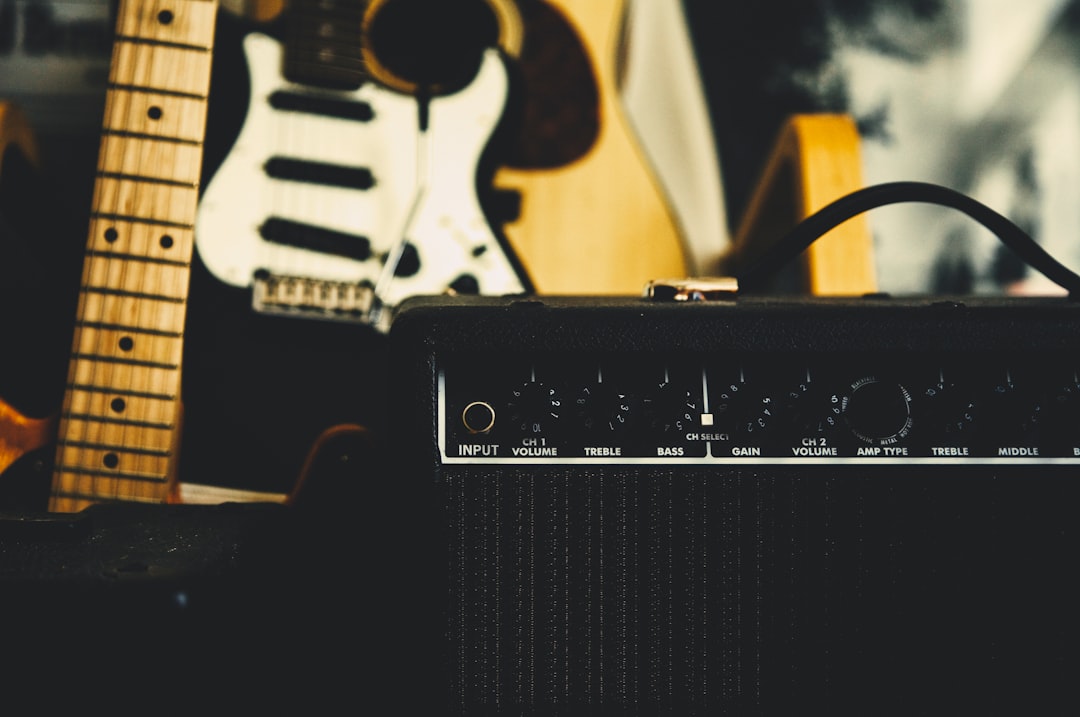 black guitar amplifier beside electric guitar,