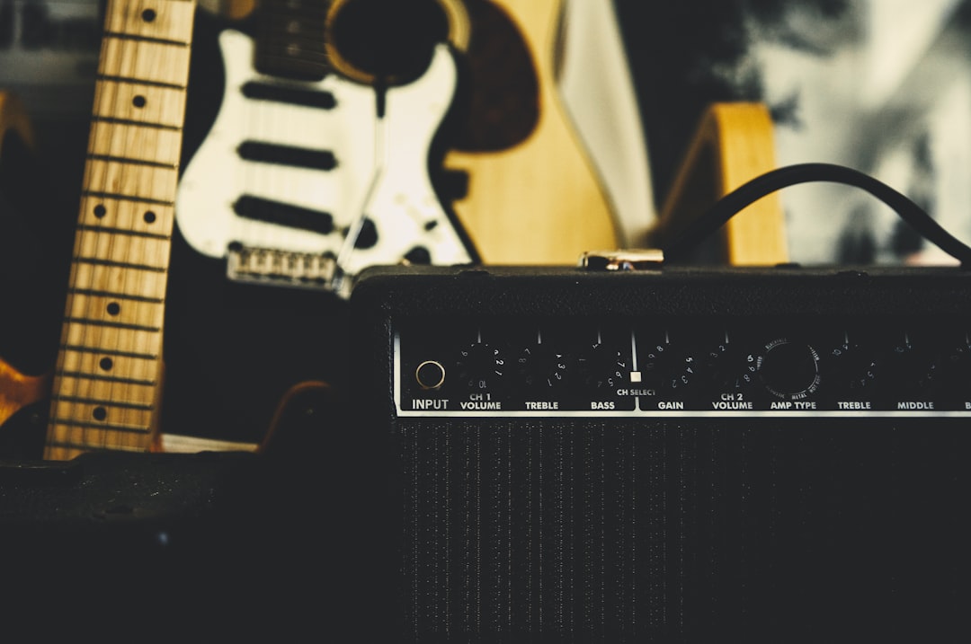 black guitar amplifier beside electric guitar,