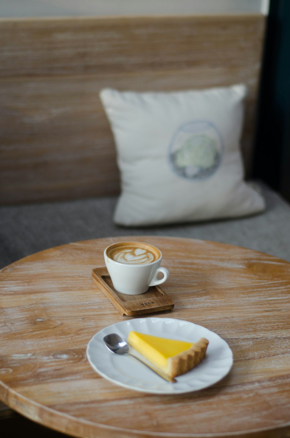 white ceramic teacup with cappuccino beside dessert on plate