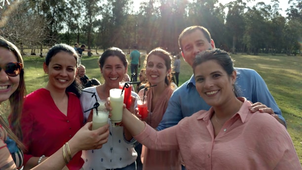 A group of diverse people enjoying energy drinks together outdoors on a sunny day.